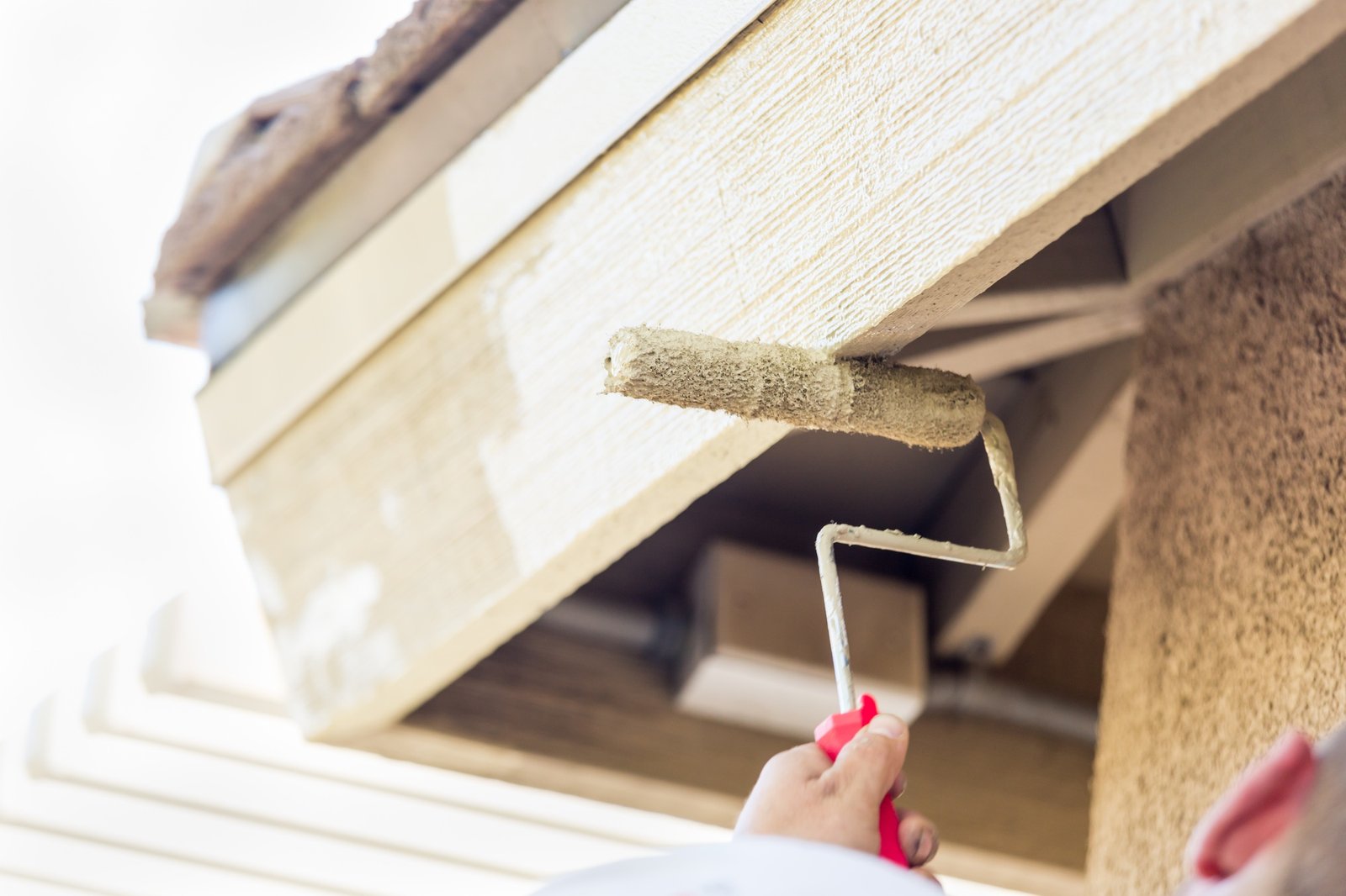 Professional Painter Using A Small Roller to Paint House Fascia.